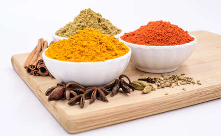 Herbs and spices such as star anise, cinnamon, turmeric, chilli powders and other on a chopping boardの写真素材