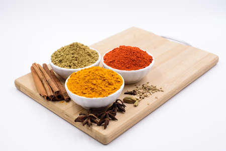 Herbs and spices such as star anise, cinnamon, turmeric, chilli powders and other on a chopping boardの写真素材