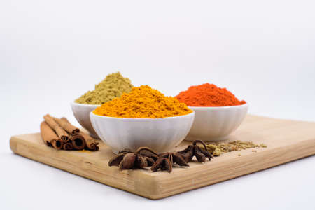 Herbs and spices such as star anise, cinnamon, turmeric, chilli powders and other on a chopping boardの写真素材