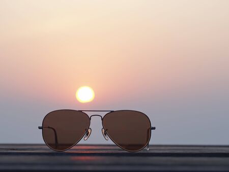 Closeup on eyeglasses with focused and blurred landscape sunset viewの写真素材