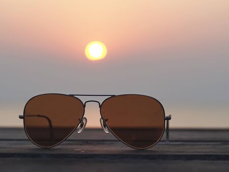 Closeup on eyeglasses with focused and blurred landscape sunset viewの写真素材
