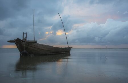 Twilight and sunset at the sea with fishing boat and cargo shipの写真素材