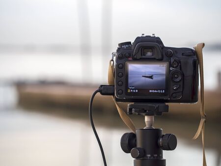 Closeup of a camera on a tripod outdoors. Background Landscape out of focus, select focusの写真素材
