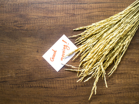 Rice and piece of paper with text "good morning" on the wooden table close-upの写真素材