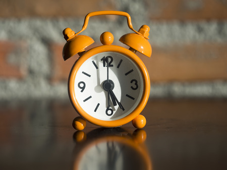 Old clock orange on the wooden table, select focusの写真素材