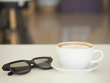 Coffee cup with glasses on wooden table ,soft focus