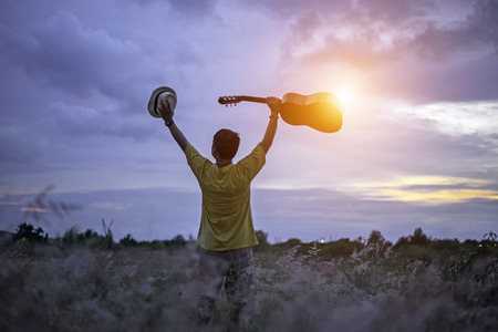Man happy with guitar in meadow. travel and sunset, soft and select focusの写真素材