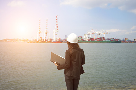 The women engineer working with container Cargo freight ship in shipyard at dusk for Logistic Import Export backgroundの写真素材