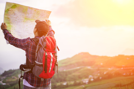 Lost hiker with backpack checks map to find directions in wilderness areaの写真素材