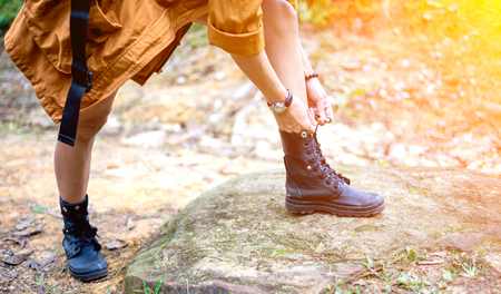 Woman hiking tying shoelace on forest trailの写真素材