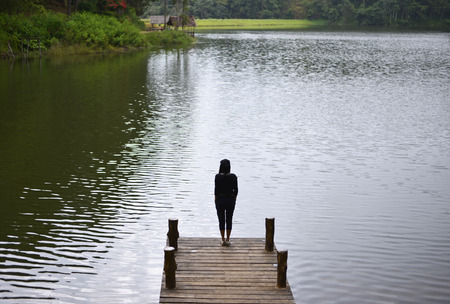 Woman feeling victorious facing on the bridge in the lake, Thailandの写真素材