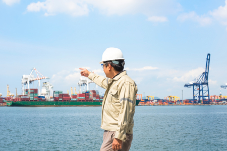 The man engineer working with container Cargo freight ship in shipyard at dusk for Logistic Import Export backgroundの写真素材