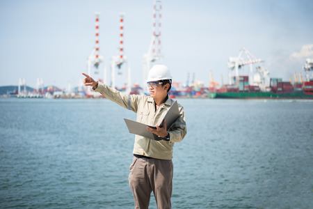 The man engineer working with container Cargo freight ship in shipyard at dusk for Logistic Import Export backgroundの写真素材