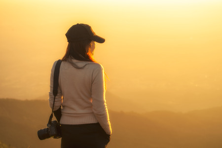Professional woman photographer see the mountain veiw in the sunriseの写真素材