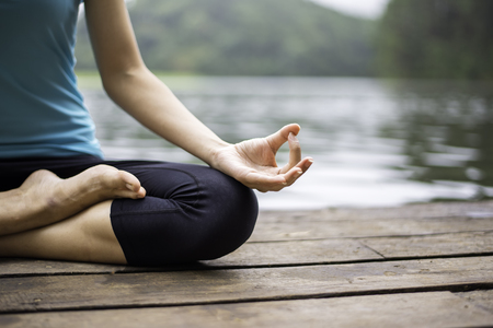 Close up hand. Woman do yoga outdoor. Woman exercising yoga at the nature background, select focusの写真素材