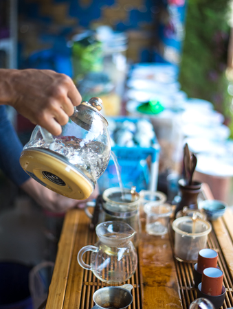 Hand that pours chinese green tea from glass kettle to smal cup, select focusの写真素材