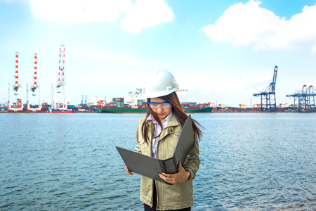 The women engineer working with container Cargo freight ship in shipyard at dusk for Logistic Import Export backgroundの写真素材