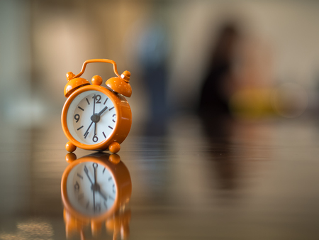 Old clock orange on the wooden table, soft and select focus