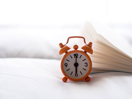 Alarm clock on bed in morning with sun lightの写真素材