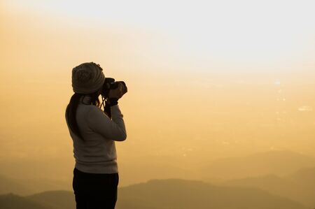Silhouette of photographer taking picture of landscape during sunset, soft and select focusの写真素材