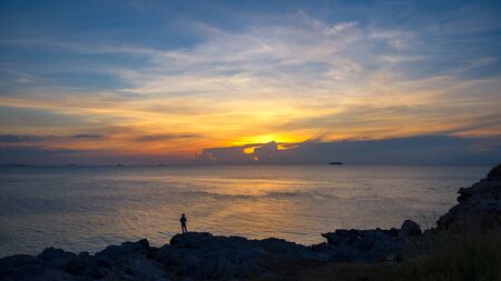 Fishermen standing on the rocks at sunsetの写真素材