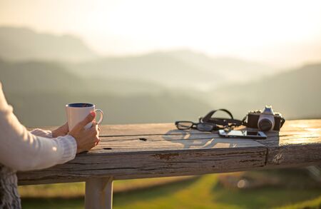Woman drinking coffee in sun sitting outdoor in sunshine light enjoying her morning coffee, vintage, soft and select focusの写真素材