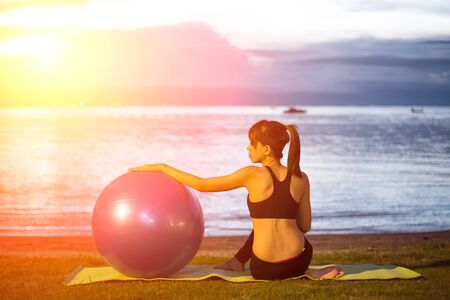 Silhouette yoga ball yung woman in the beach sunset backgroundの写真素材