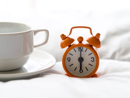 Fresh morning coffee and clock on the bed.の写真素材