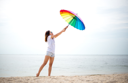 Young women jumping with umbella and happy on the beach. Travel and Vacation. Freedom Conceptの写真素材