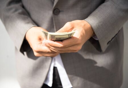 Business executive in formal suit giving money as a bribe, select focusの写真素材