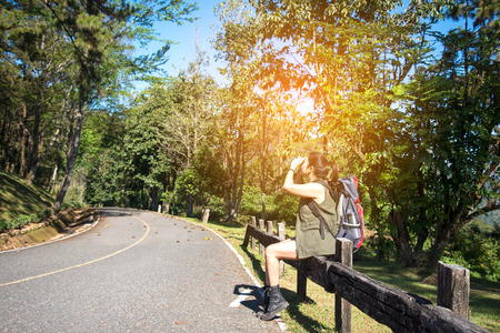 Hiker woman look binoculars on the road in the forestの写真素材