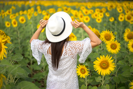 Beautiful girl in field of sunflowers, so happy and relaxの写真素材