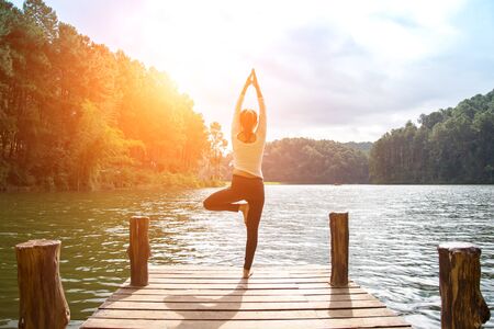 Healthy woman practicing yoga on the bridge in the natureの写真素材