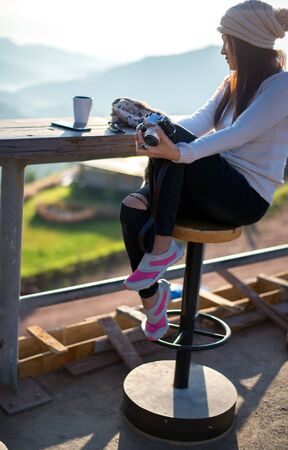 Woman drinking coffee in sun sitting outdoor in sunshine light enjoying her morning coffee,  soft and select focusの写真素材