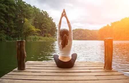 Woman do yoga outdoor. Woman exercising yoga at the nature background, select focusの写真素材
