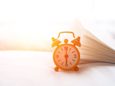Alarm clock on bed in morning with sun lightの写真素材