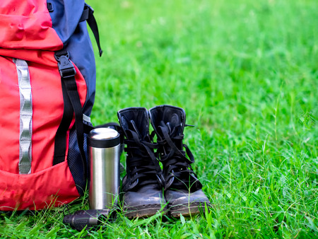 Hiking travel gear on glasses. Items include hiking boots, cup, map,binoculars. Flat lay of outdoor travel equipment items for mountain camping trip. Greenery tone 2017の写真素材