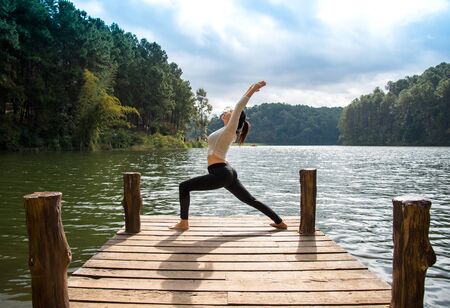 Healthy woman practicing yoga on the bridge in the natureの写真素材