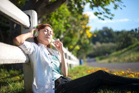 Young women lying in summer grass with headphones listening to music and relaxing, Greeney Tone 2017の写真素材