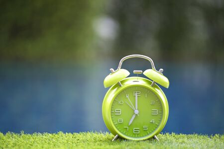 Retro alarm clock on table near swimming pool, greenery toneの写真素材