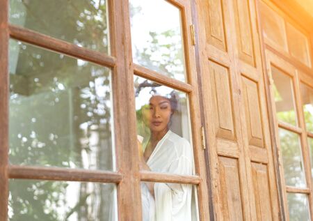 Getting warm with fresh coffee. Beautiful young woman drinking coffee and looking through a window