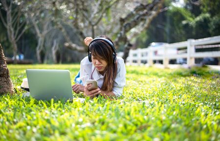 Woman working with computer in the park, greenery toneの写真素材