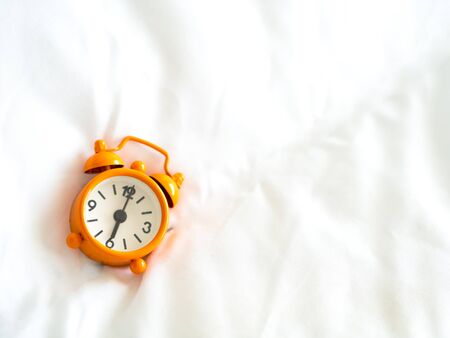 Alarm clock on bed in morning with sun lightの写真素材