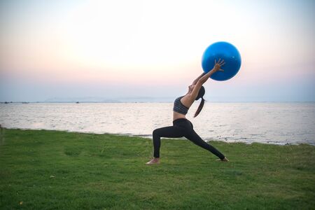 Silhouette yoga ball yong woman in the beach sunset backgroundの写真素材