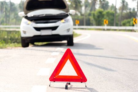 Red emergency stop sign and broken silver car on the roadの写真素材