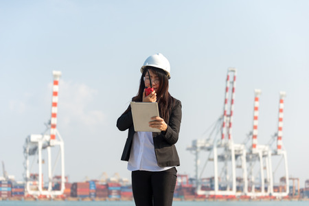 The women engineer working with container Cargo freight ship in shipyard at dusk for Logistic Import Export backgroundの写真素材