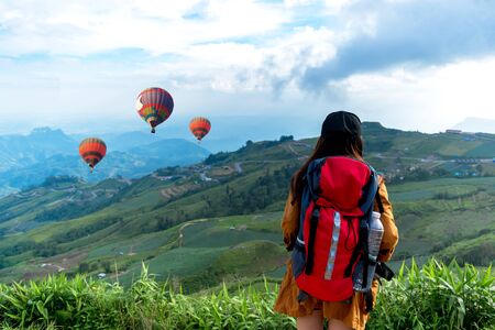 Hiker woman feeling victorious facing and seeing balloon on the mountain, Thailandの写真素材