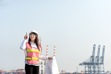 The women engineer working with container Cargo freight ship in shipyard at dusk for Logistic Import Export backgroundの写真素材