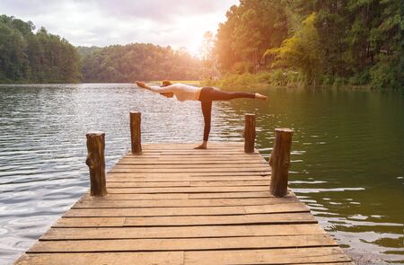 Healthy woman practicing yoga on the bridge in the natureの写真素材