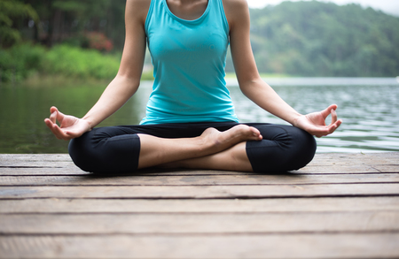 Healthy woman practicing yoga on the bridge in the natureの写真素材